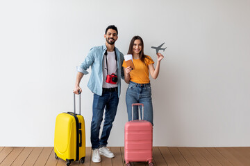 Travel abroad concept. Joyful couple ready for vacation, woman holding little plane model and...