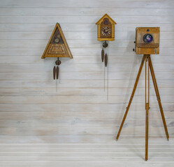 Antique wooden clock and antique wooden camera on a light wooden background
