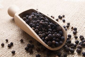 black peppercorns on a wooden scoop