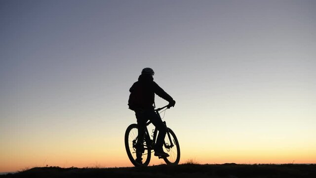 Silhouette of man riding on mountain bike at sunrise