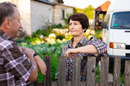 Neighbors Man And Woman Chatting Near The Fence In The Village