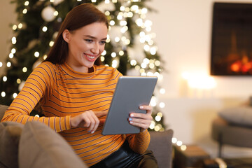 Smiling young woman using digital tablet at home