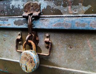 A close up shot of an old vintage metal trunk with a big lock .