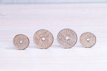 Norwegian krone (NOK) coins with hole on wooden table.