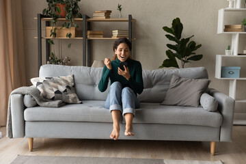 Obraz premium Full length euphoric sincere young woman feeling overjoyed, reading message with unbelievable amazing news on cellphone, celebrating online lottery win or auction betting gambling victory at home.