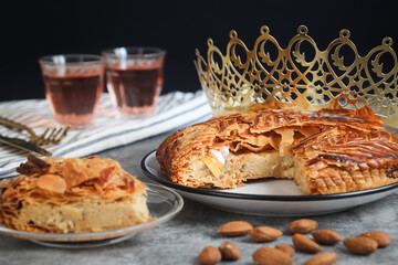 A pieces of traditional French galette des rois or King cake, with crown and fève. Glass of cider....