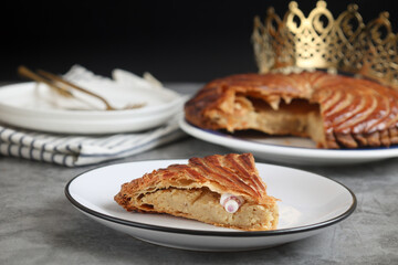 A cut piece of traditional French galette des rois or King cake, with fève inside. Cake made with...