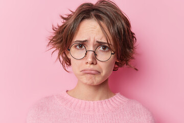 Portrait of sulking displeased woman looks sadly purses lips feels unhappy and frustrated finds out...