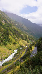 Fototapeta na wymiar Mountain valley in Switzerland, river, road, dense forest and fog