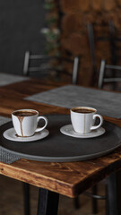 two mugs of coffee stands on a tray in a restaurant.  dark colors, loft style interior.  no people