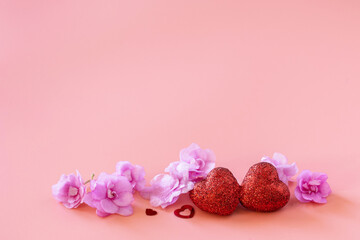 Valentines, love and wedding concept. Lilac violet flowers and red hearts on pink background. Copy space.