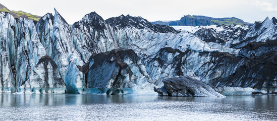 Sólheimajökull picturesque glacier in southern Iceland. The tongue of this glacier slides from the volcano Katla. Beautiful glacial lagoon with blocks of ice and surrounding mountains.