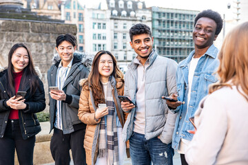 Happy group of friends in the city using mobile phones and laughing together - 480716678