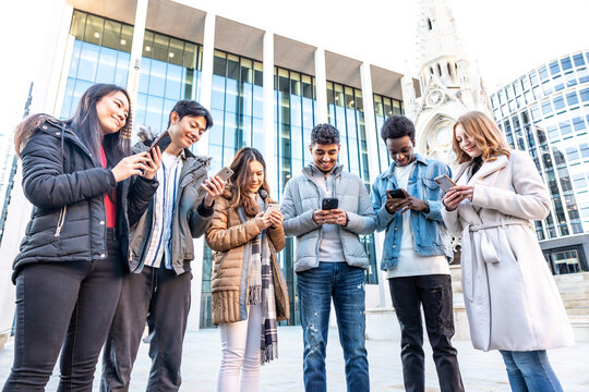 Mixed race group of friends in the city using mobile phones and ignoring each other