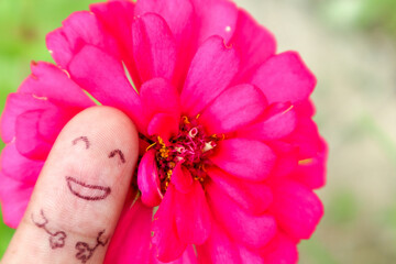 Photo finger with emotion smile and pink flower as background