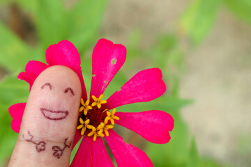 Photo finger with emotion smile and pink flower as background