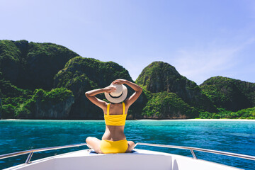 Rear view of adult traveling woman relax on the sailing boat with summer island and sea