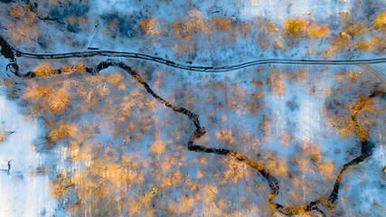 Aerial view of the river on a snowy forest plain during a clear winter morning and bright sunrise