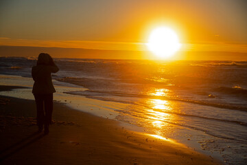 Fototapeta na wymiar Silhouette of a young woman at the beach enjoying sunset