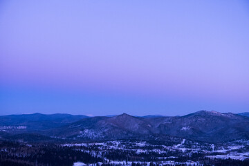 Russia. Sheregesh. Sunset in purple tones. View of snowy mountains and forest