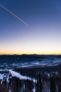 Sheregesh. Russia. A Bright Orange Dawn Among The Mountains And An Urban Village With Small Houses And A Coal Mine. The Trace Of The Plane Is Visible In The Sky. View From Above.