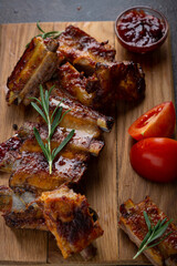 Roasted ribs with sauce and tomatoes on wooden board