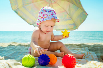 The baby is playing on the beach. Child at sea. Toys for sand and water. Sun protection for young...