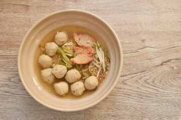 boiled barbecue pork and meatball topping slice yard long bean and bean sprout called Thai Sukhothai noodle spicy sour tom yum soup on bowl