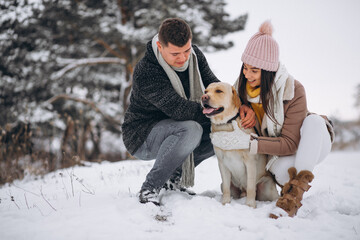 Fototapeta na wymiar Family walking in winter park with their dog
