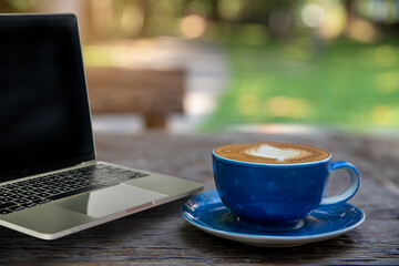 Laptop  and coffee cup of latte art fresh on wooden table in cafe.. morning coffee, coffee time concept.