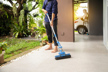 Male janitor with mop cleaning modern house floor.