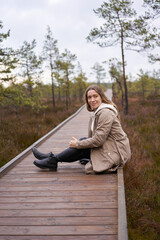 Lifestyle photo A girl trench coat in nature.  viru bog trail in Estonia. Travel,  exploration, healthy lifestyle, active rest