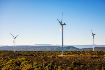 Obraz premium Wind turbines on a beautiful blue sky in a mountain wind farm in Sardinia. Renewable energy concept, green energy generation. Energy industry.