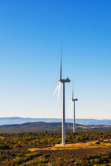 Wind turbines on a beautiful blue sky in a mountain wind farm in Sardinia. Renewable energy concept, green energy generation. Energy industry.