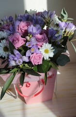 A bouquet of pink roses, white chamomile and blue freesias.	