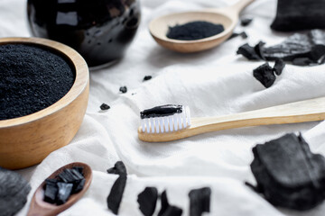 Black charcoal toothpaste with finely ground charcoal is placed on a white cloth.
