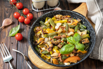 Seafood ragout, healthy mediterranean dinner. Seafood shrimps, calamari, cuttlefish stewed with vegetables and garlic sauce in a frying pan, on an wooden table.