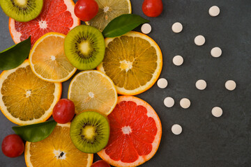 Vitamin concept. Fresh juicy sliced citrus fruits next to vitamin C tablets. Choice between healthy eco food and supplements.