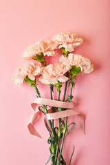 Bouquet of pink carnations. Design concept of holiday greeting with carnation bouquet on pink table background