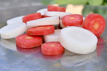 closeup the bunch sliced red carrot with white radish over out of focus grey green background.