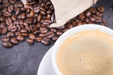 Coffee in white cup and roasted dark coffee beans in bag