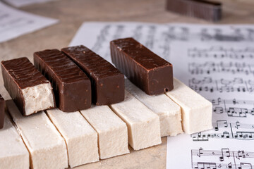 Piano keyboard stacked with white and chocolate marshmallows, selective focus