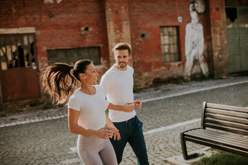 Young fitness couple running in urban area