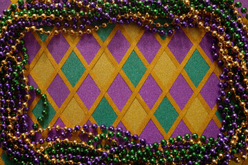 Frame of colorful Mardi Gras Beads on diamond shaped background