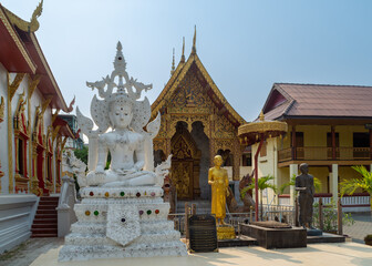 Obraz premium A sculpture of Buddha at the buddhist temple Wat Tung Yu in Chiang Mai, Thailand. In the background are the Viharan (Main Hall) and Ubosot (Ordination Hall).