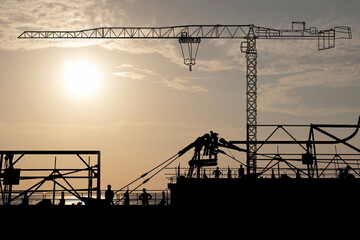 At the construction site was there are workers dismantling the tower crane and another tower crane...