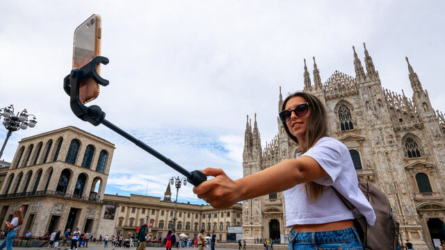 Travel influencers Milan island. Paint building house in Europe Milano. Photographer blogger girl with smartphone in Piazza del Duomo, Cathedral Square. Traveling and freelancing, modern lifestyle.