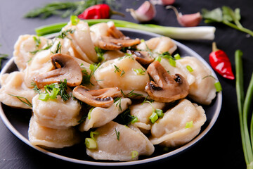 Dumplings with mushrooms on a black background with onions, garlic and eggs. Vareniki is a dish of Slavic cuisine.