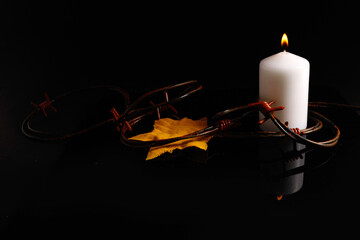 Holocaust memory day. Arbed wire and burning candle on black background