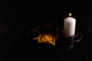 Holocaust memory day. Arbed wire and burning candle on black background